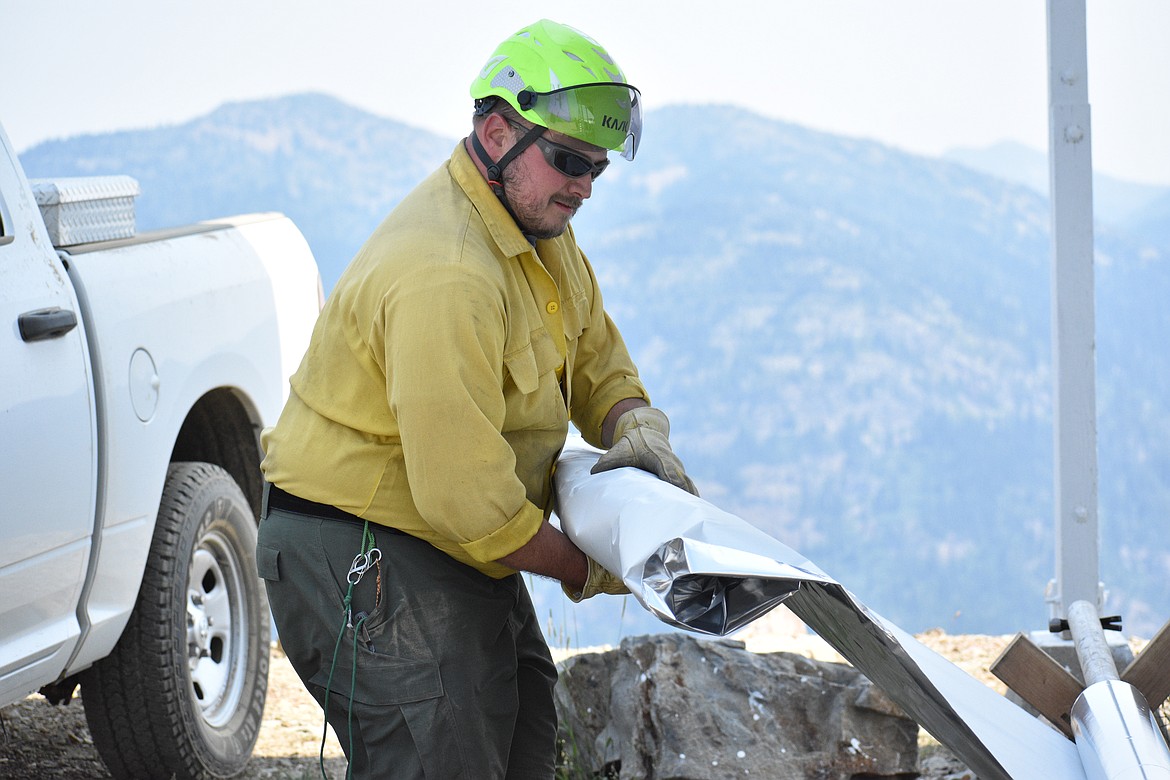 Christian Goodlander rolls up the aluminized fiberglass wrap and prepares to cut off a piece on Saturday.