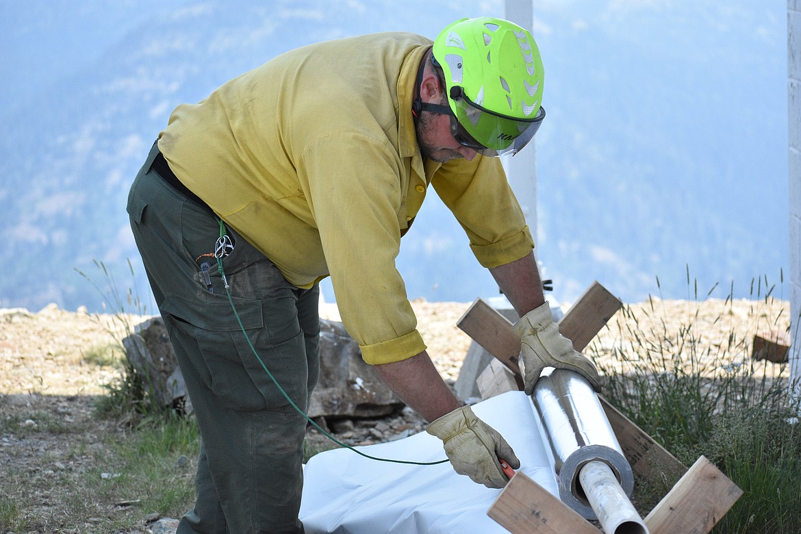 Christian Goodlander cuts off a piece of wrap for the tower on Saturday.