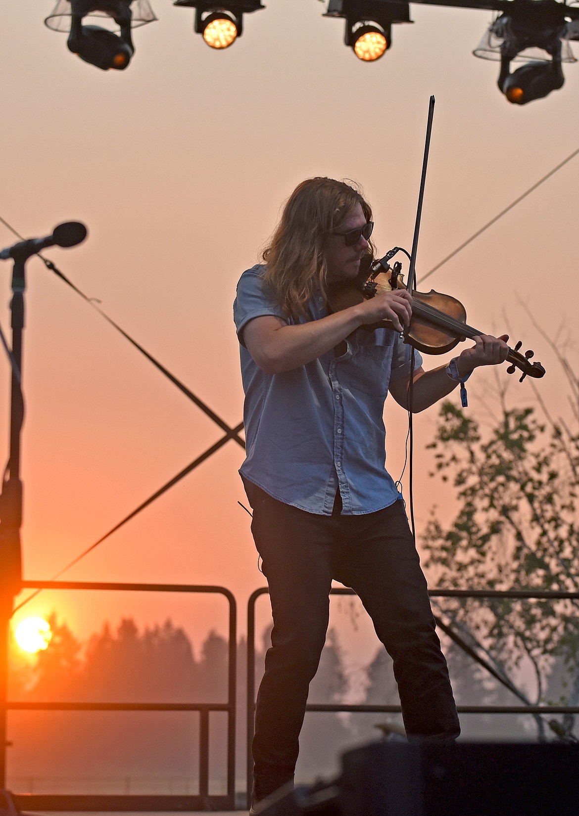 The Lil Smokies fiddlist Jake Simpson plays as the sun sets behind him at the Under The Big Sky Festival in Whitefish on Saturday. (Whitney England/Whitefish Pilot)
