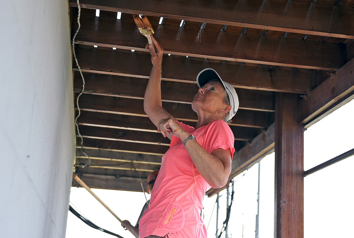 Northwest Montana Lookout Association volunteer Barb Hvizdak paints stain on the underside of the deck at the Werner Peak Lookout during a recent restoration project. (Whitney England/Whitefish Pilot)
