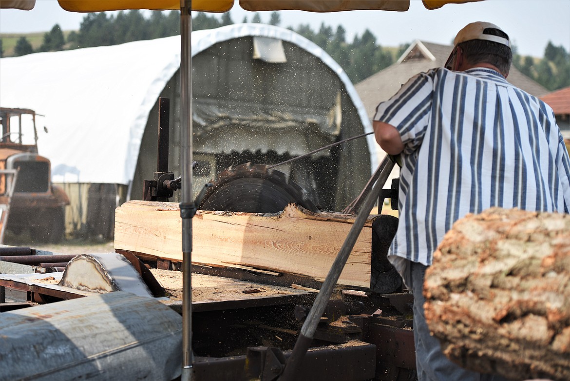 Live History Days volunteer Larry Eslick of Marion runs a saw that's about 100 years old. Eslick and a crew of three others -- Sawyer Thome of St. Ignatius, Anthony Barone of Marion and Steve Martin of Kalispell -- ripped several planks of logs throughout the event. (Scot Heisel/Lake County Leader)