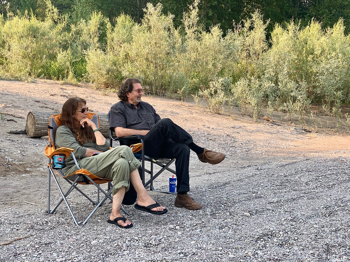 Lori and Randy Holgate take in the evening along the banks of the Flathead River at the Old Steel Bridge fishing access site in Evergreen on Friday, July 16, 2021. (Mackenzie Reiss/Daily Inter Lake)