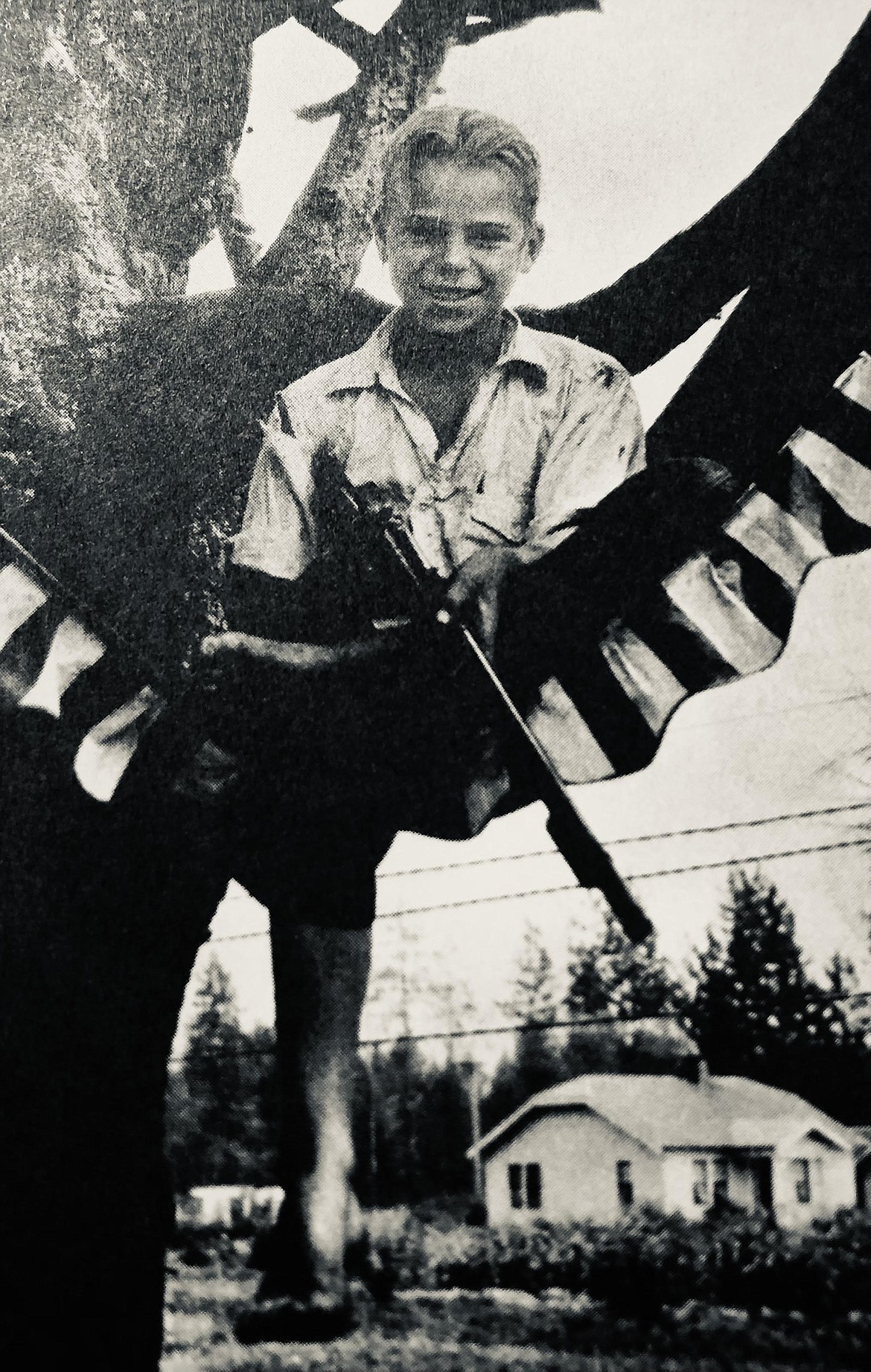 A photo from Louise Shadduck's book, "At the Edge of the Ice" about Elmo Wilcox, 13, who stayed in a tree from mid-July until school bells in September 1930. Elmo is holding a fake machine-gun in the photo (to keep marauders away from his treehouse).