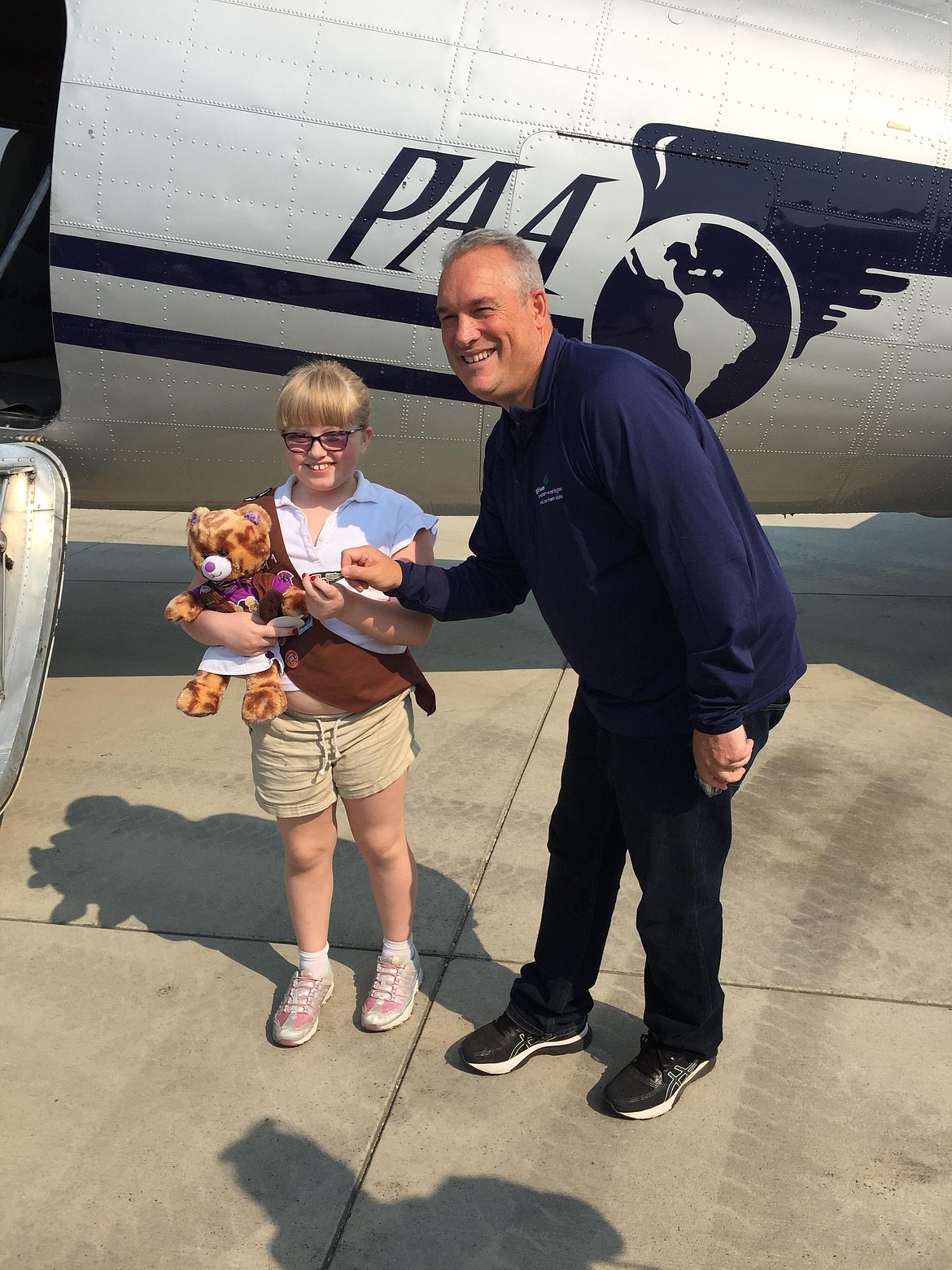 Faith Bailey, 8, stands next to CEO of Girl Scouts, Eastern Washington and Northern Idaho, Brian Newberry. Newberry presented scouts with their wing badges after a hour-long flight in a DC-3 as a reward for selling the most Girl Scout Cookies in the region.