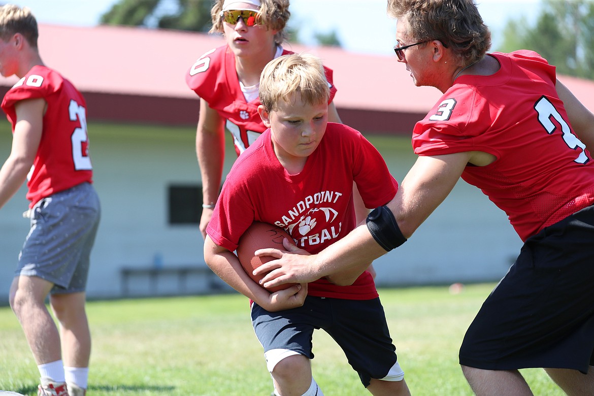 A camper fights through contact from Blake Sherrill (right) during running back drills on Friday.