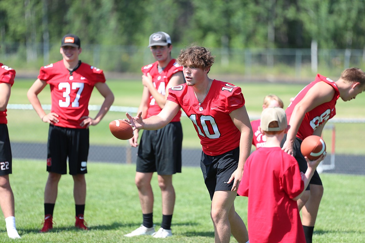 Arie VanDenBerg tosses a ball to a camper during wide receiver drills on Friday.
