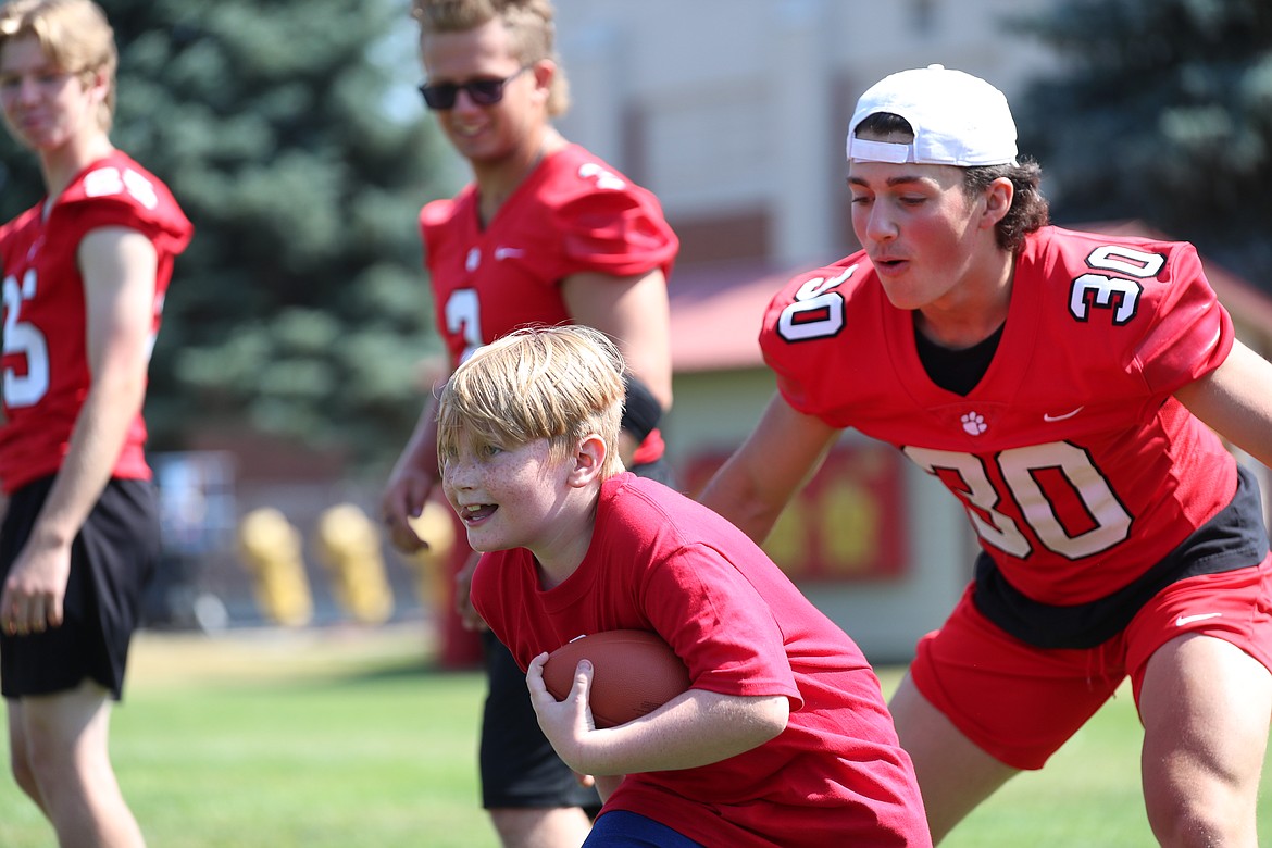A camper tries to spin past a varsity player during running back drills on Friday.