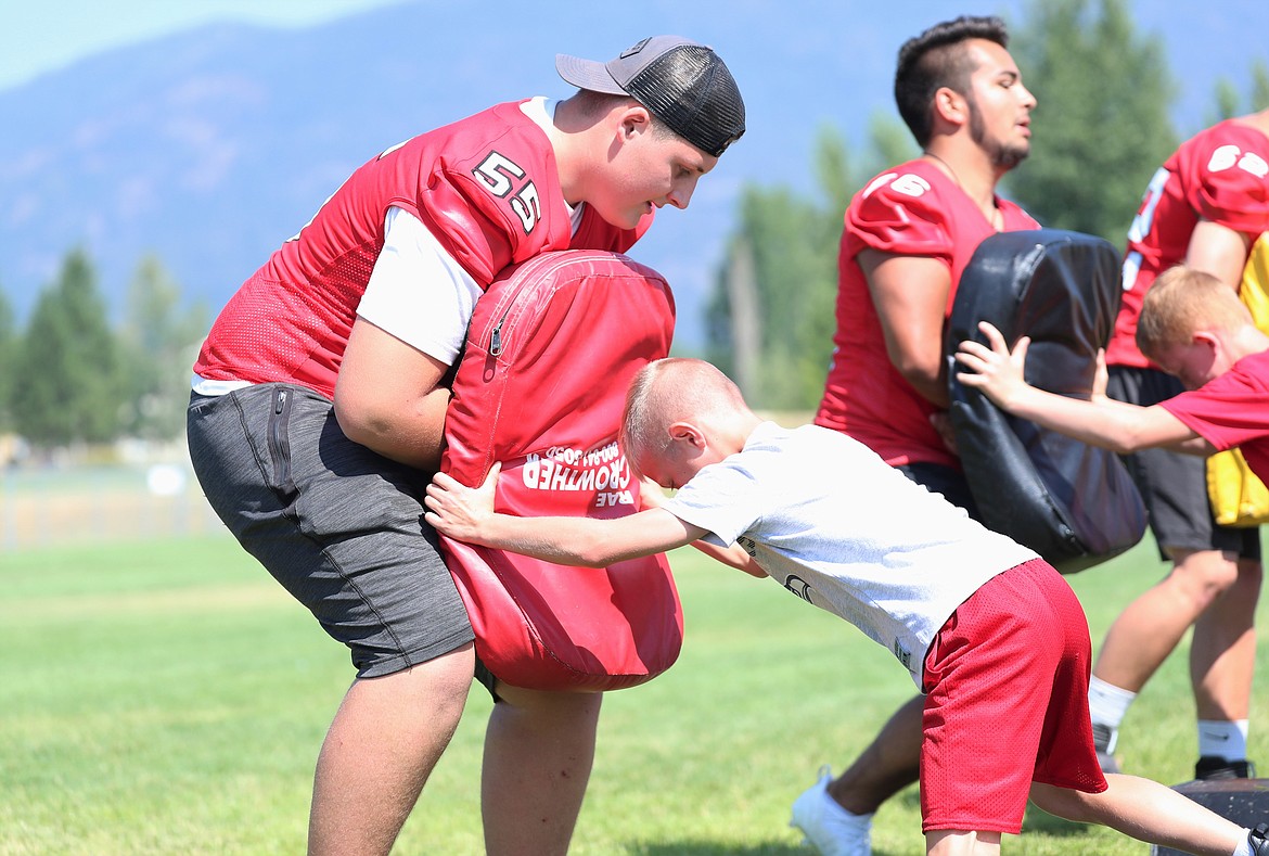Carson Laybourne helps a youngster through offensive line drills on Friday.