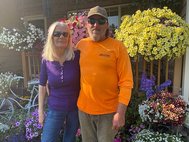 Duff and Bonny Angle stand in front of the voluminous blossoms adorning their home - "Last year the hanging baskets grew all the way to the ground," Bonny said.