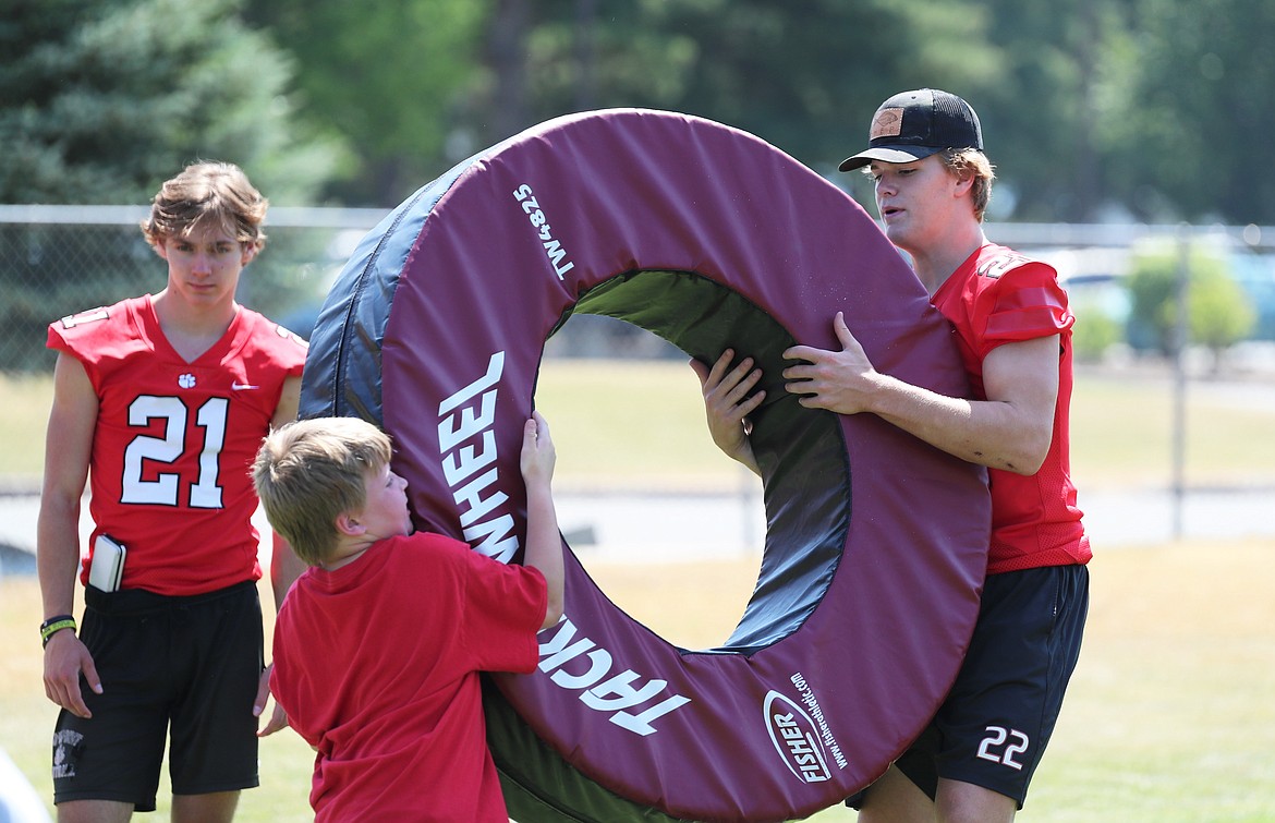 Wes Benefield holds the tackling wheel for a camper during drills on Friday.