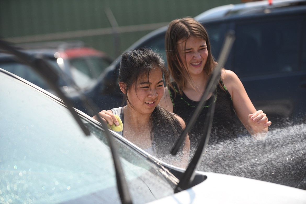 Noxon volleyball players Martha Klaus, left, and Seanna Richter, try to avoid the spray from a hose at last Saturday’s car wash at the Trout Creek Town Store. (Scott Shindledecker/Valley Press)