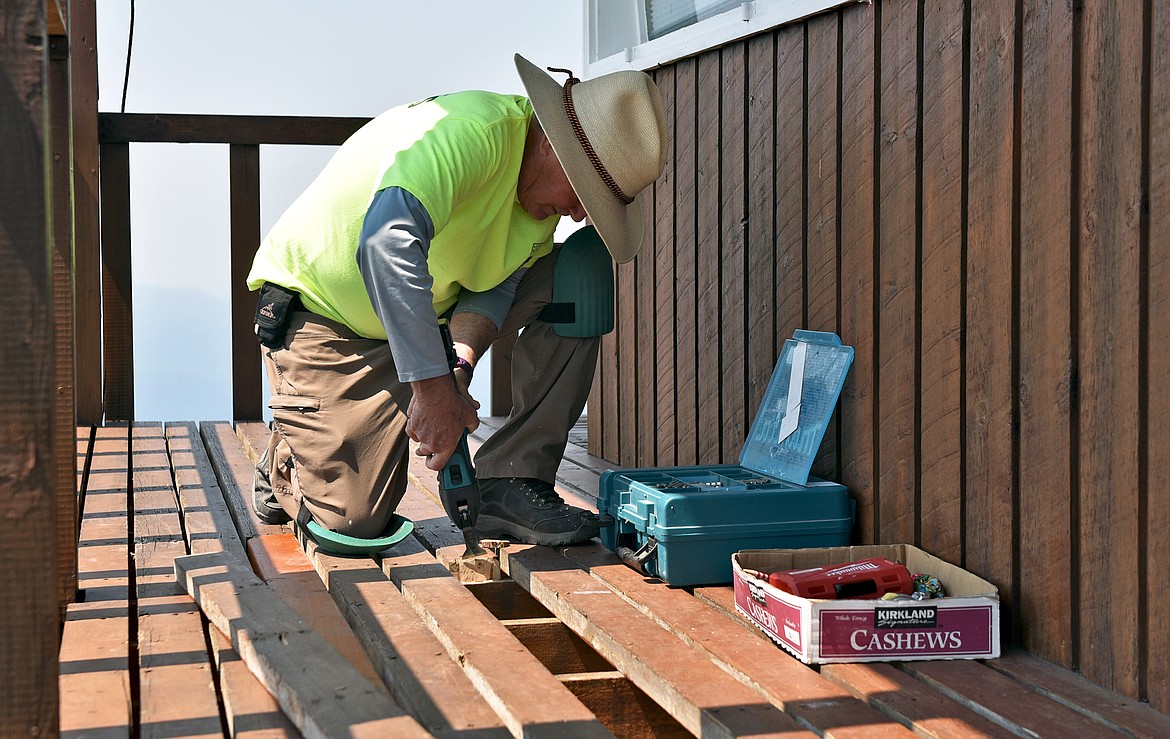 Northwest Montana Lookout Association volunteer project leader Rick Davis works to replace decking boards at the Werner Peak Lookout during a recent restoration project. (Whitney England/Whitefish Pilot)