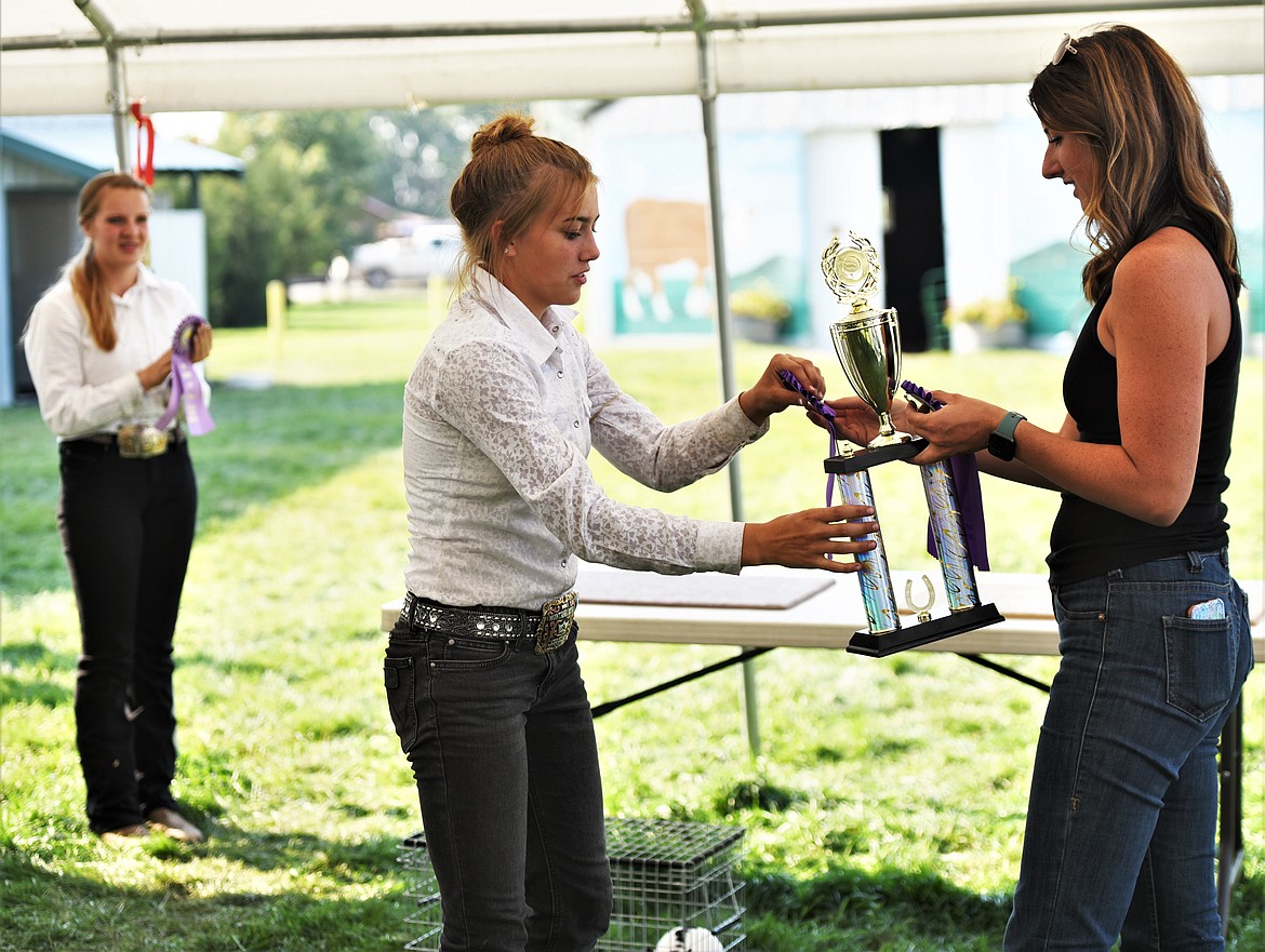 Judge Nicole Lake awards the senior small animal showmanship trophy to Maddy Evelo, while reserve champion Kaydee Wheeler watches at left. (Scot Heisel/Lake County Leader)