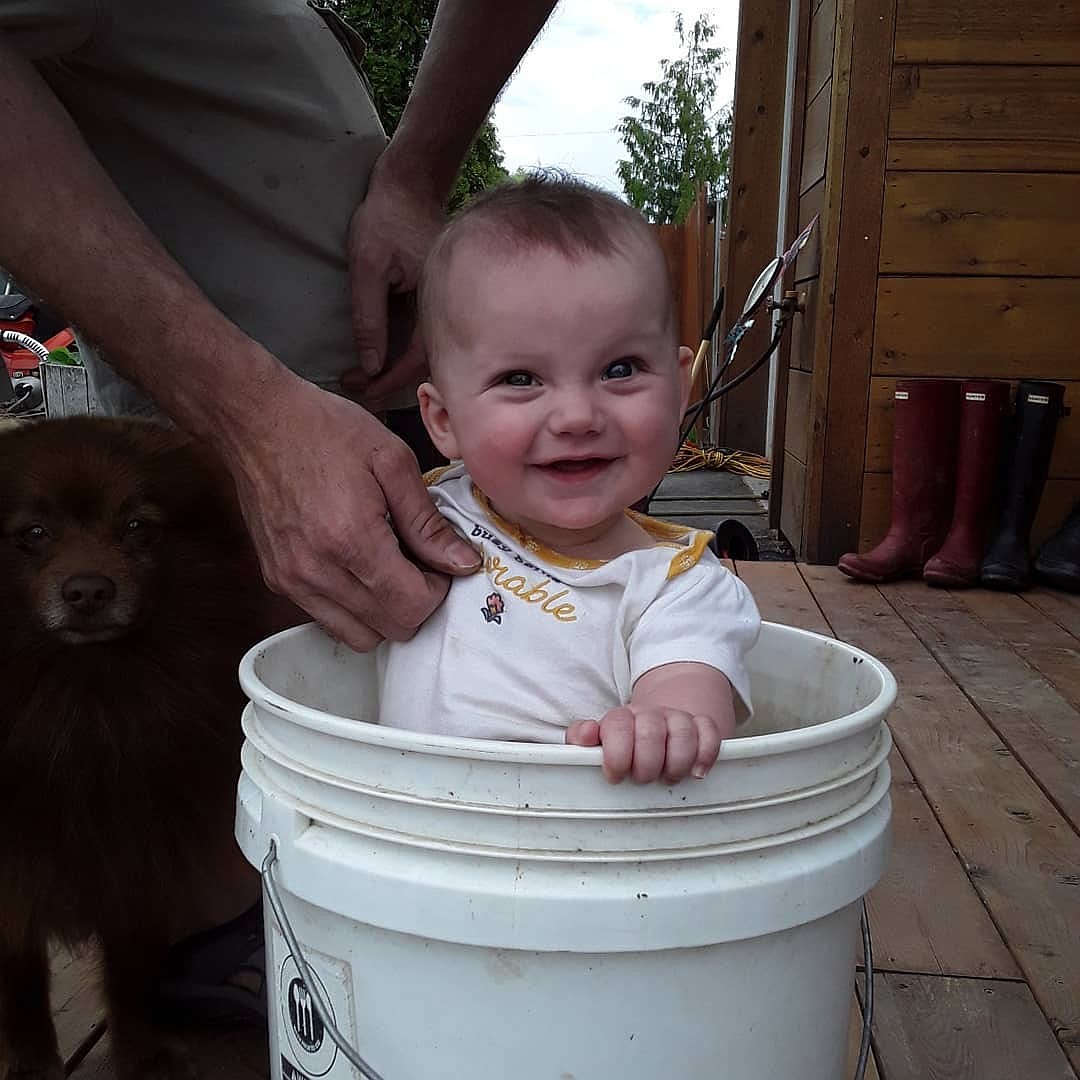 Hawks' daughter, Waverly, sits in a bucket near the family garden.