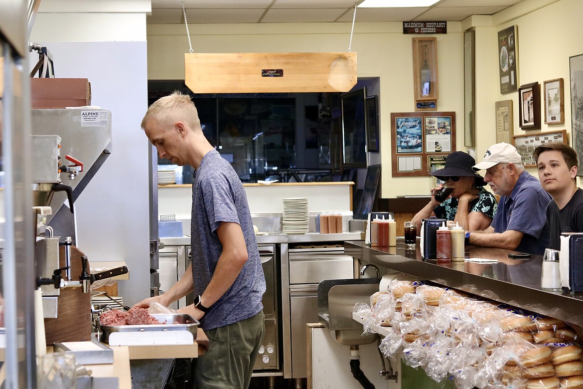 Jeremy Babcock flips patties at Hudson's Hamburgers on Sherman Avenue in downtown Coeur d'Alene Friday. The burger joint was 40th on the list for Big 7 Travel’s annual release of “The 50 Best Burgers in the United States.” HANNAH NEFF/Press