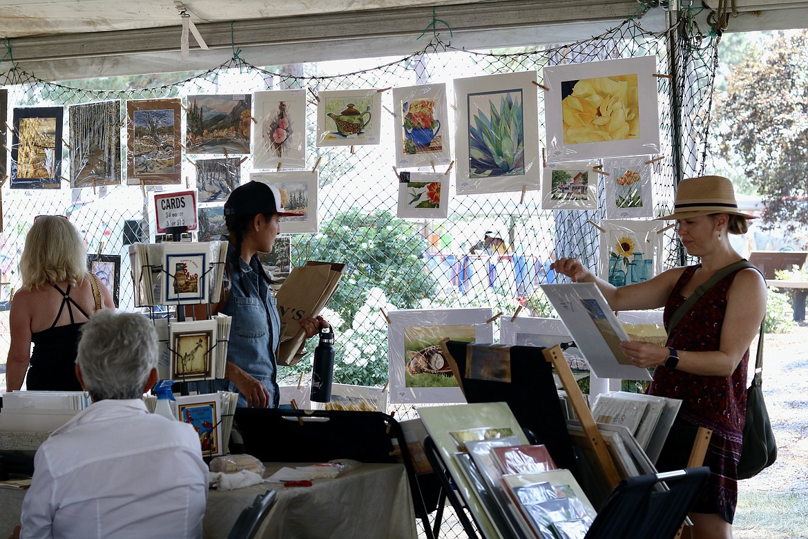 People view artwork at the juried art show during Art on the Green on Friday at the North Idaho College campus. The show runs through Sunday. HANNAH NEFF/Press