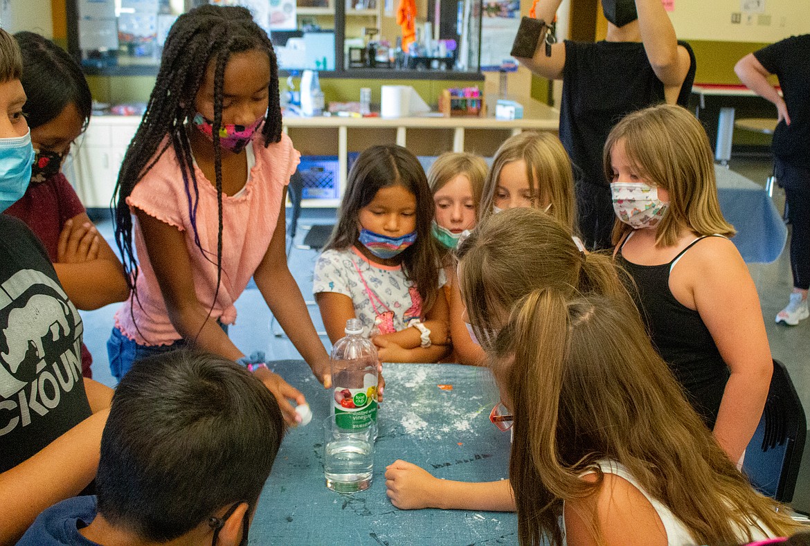 Boys & Girls Clubs of The Columbia Basin members watch a science experiment involving chalk and baking soda to demonstrate the damage certain foods can have on teeth.