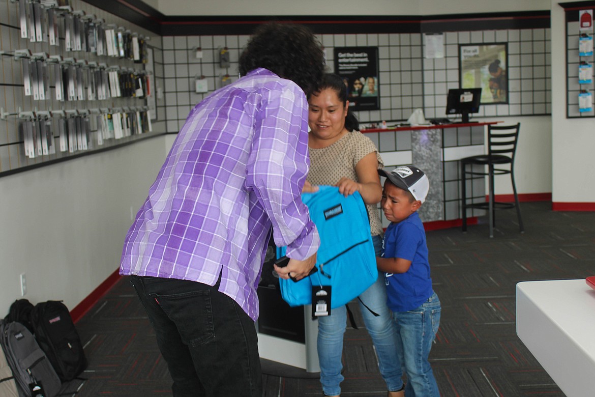 Ephrata student Juan Bastida, right, chooses a blue backpack at the Verizon-Cellular Plus backpack giveaway on Saturday.