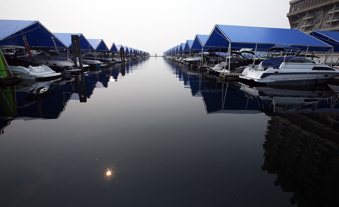 The sun peeks through the smoke and reflects off the waters of Lake Coeur d'Alene at The Coeur d'Alene Resort marina Monday.