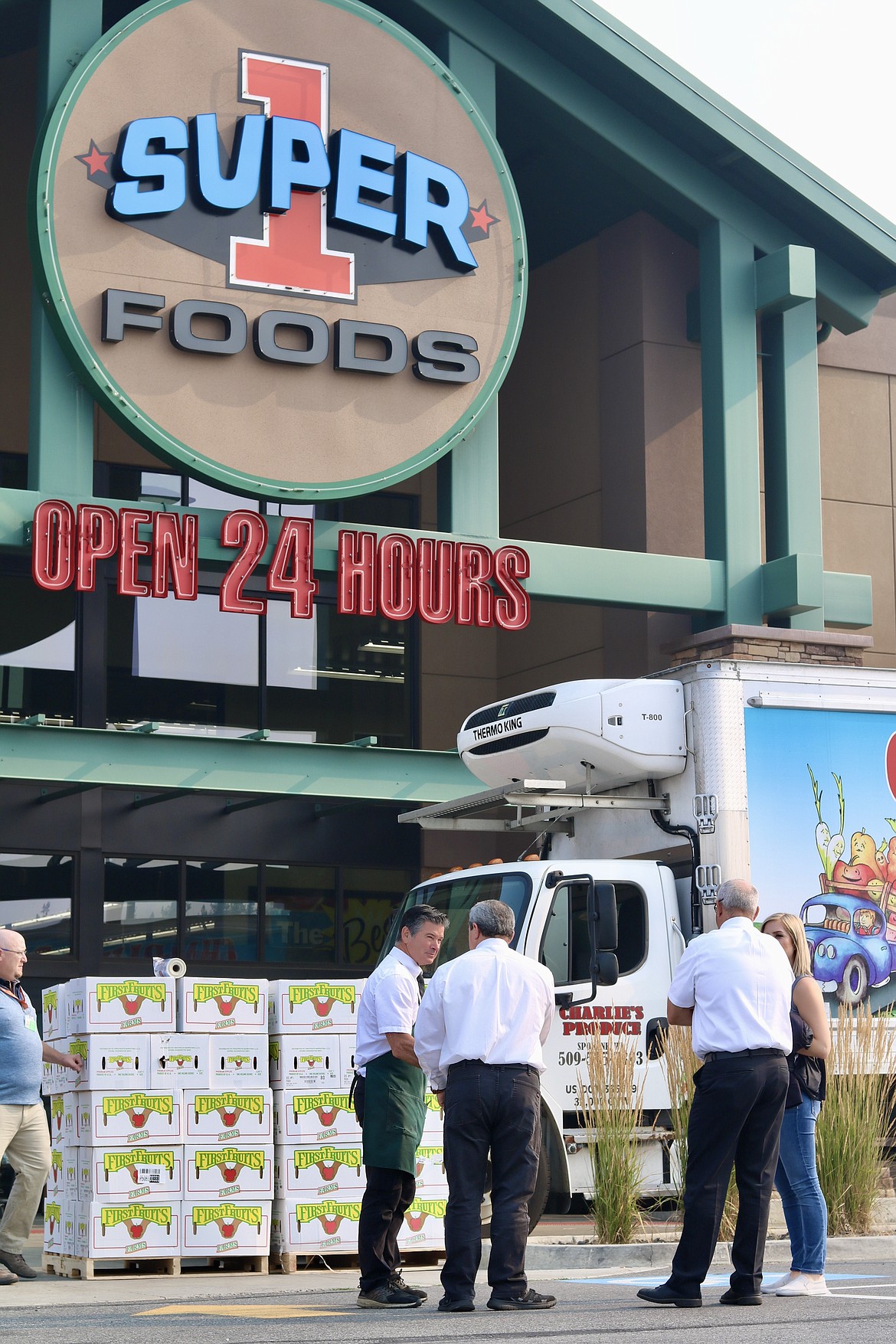 Representatives from FirstFruits, Charlie's Produce and Super 1 Foods chat while waiting for apples to be unloaded in front of the store location for a photo opportunity before they are donated to ABC Food Bank. HANNAH NEFF/Press