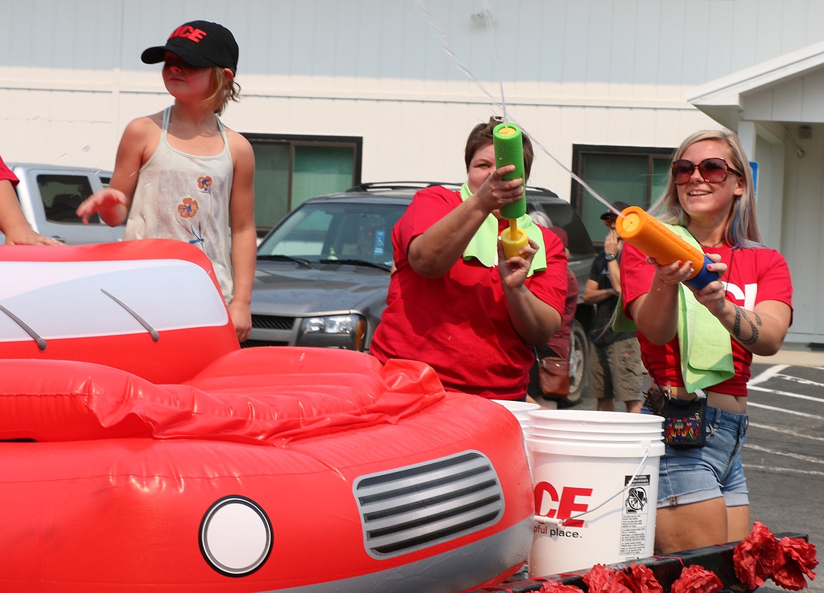 Members of the Ace Hardware float work to keep the crowd cool during a hot Timber Days parade on Saturday.