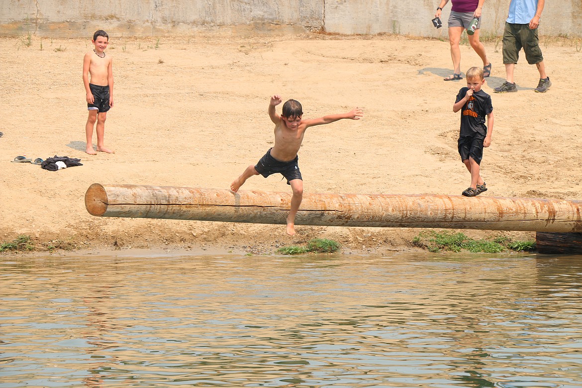 A youngster jumps off a pole into the Pend Oreille River prior to the start of Saturday's Timber Days competitions.