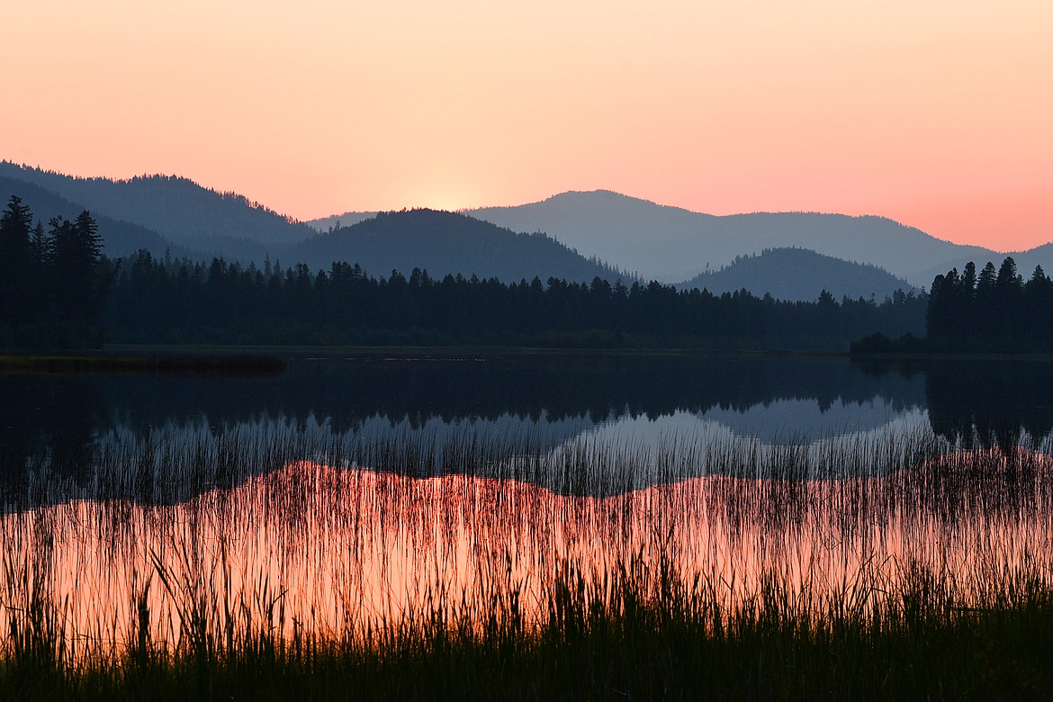 The sun dips behind a ridgeline seen from the shore of Upper Thompson Lake in Lincoln County on Saturday, July 24, 2021. (Casey Kreider/Daily Inter Lake)