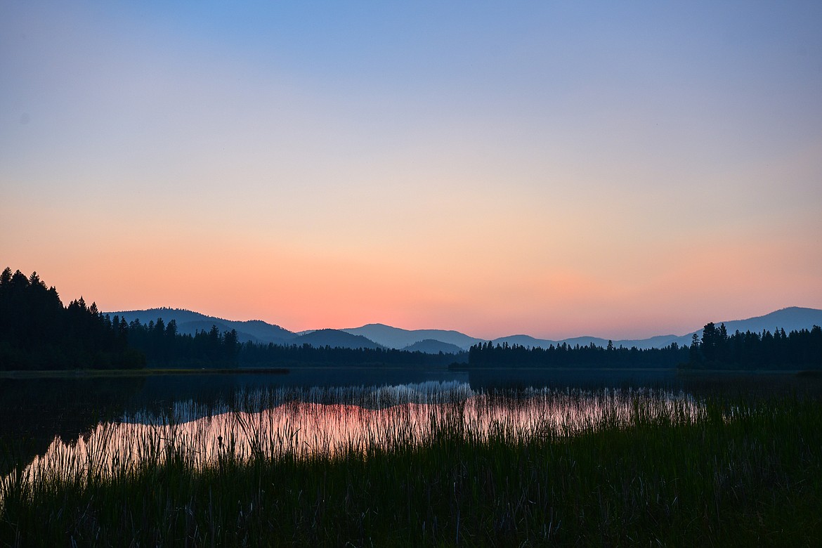 The sun dips behind a ridgeline seen from the shore of Upper Thompson Lake in Lincoln County on Saturday, July 24, 2021. (Casey Kreider/Daily Inter Lake)