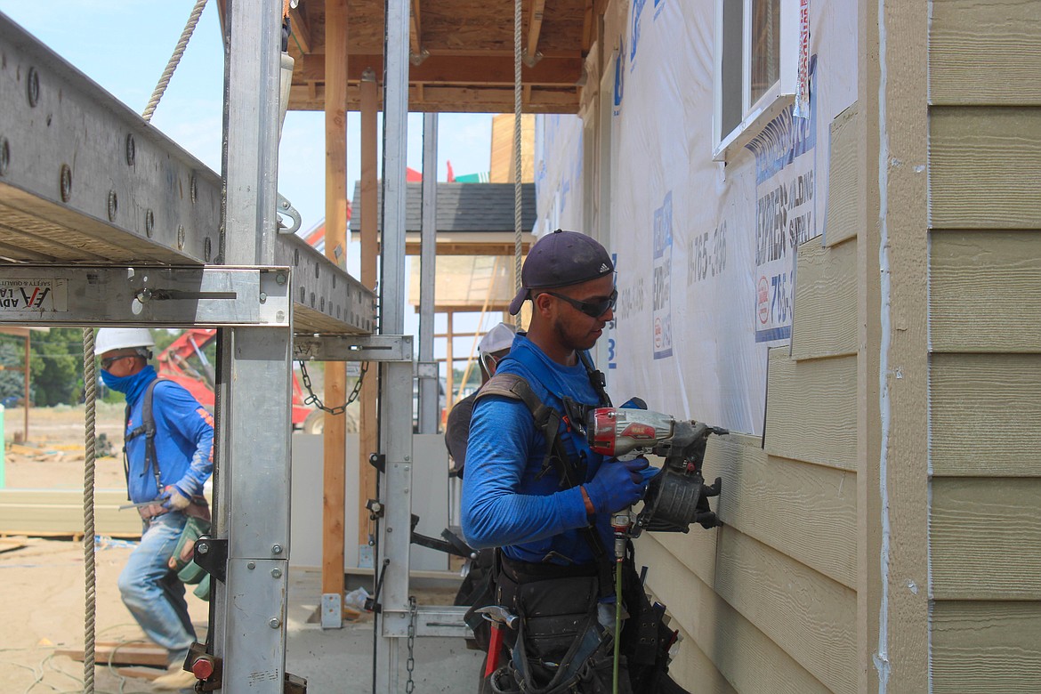 Eduardo Ochoa of Nova Construction LLC attaches siding to a new apartment complex on West Marina Drive in Moses Lake.