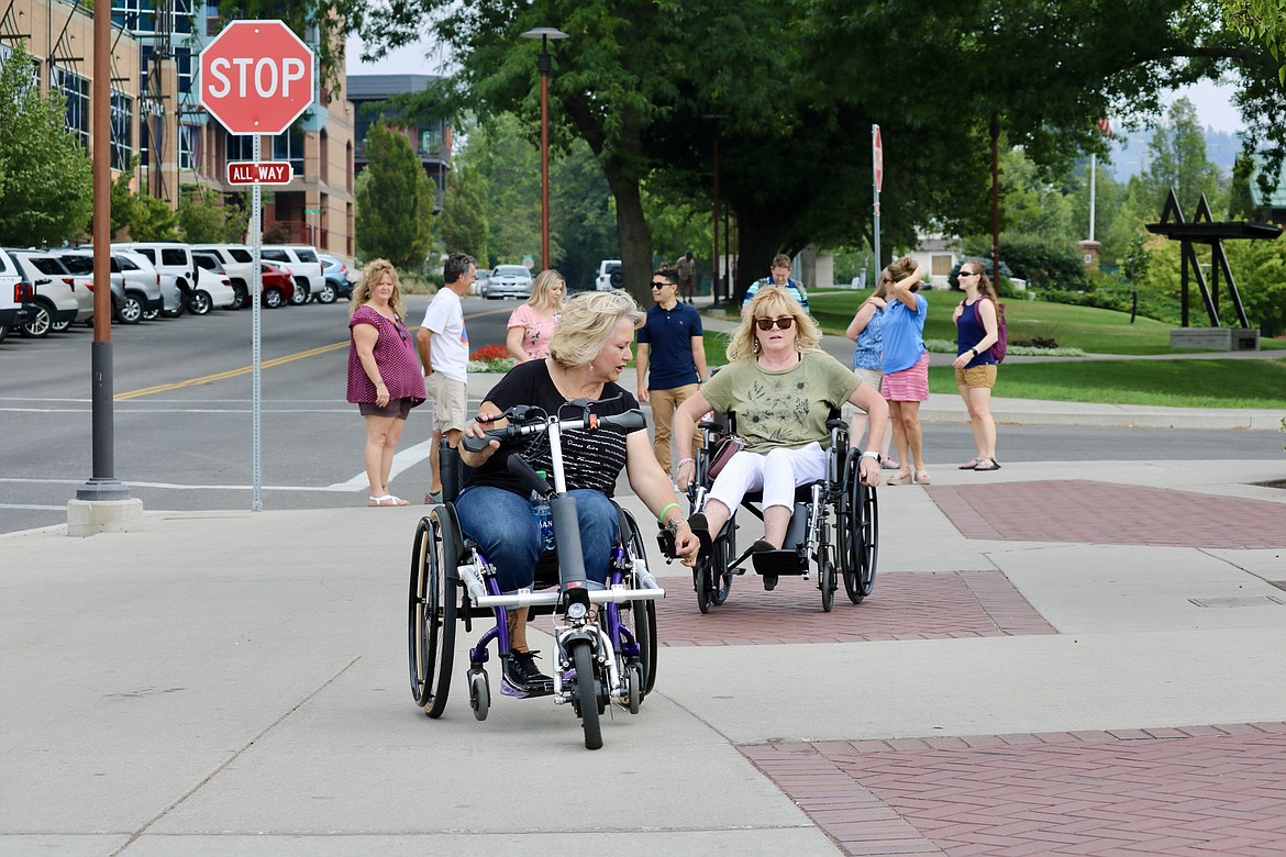 Denise Jeska, left on wheelchair, member of the Coeur d’Alene pedestrian and bicycle advisory committee, points out to Councilwoman Christie Wood, right on wheelchair, areas in the sidewalk that make maneuvering through downtown difficult for the disabled. HANNAH NEFF/Press