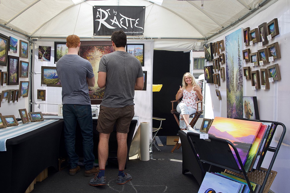 Kalispell artist Raette Merideth gives a thumbs up in her booth featuring her oil landscapes at the Bigfork Festival of the Arts. (Kay Bjork photo)