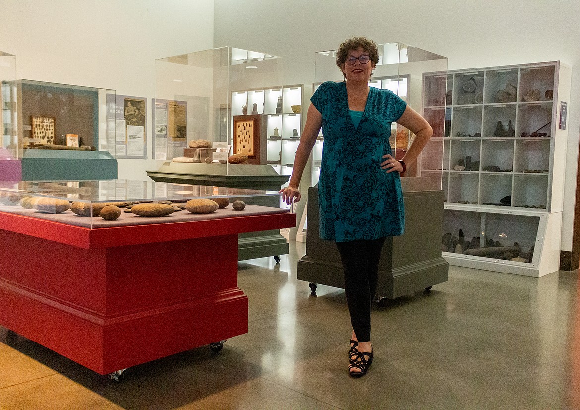 Moses Lake Museum & Art Center Manager Dollie Boyd stands in front of exhibits from the Adam East archaeological collection at the museum.