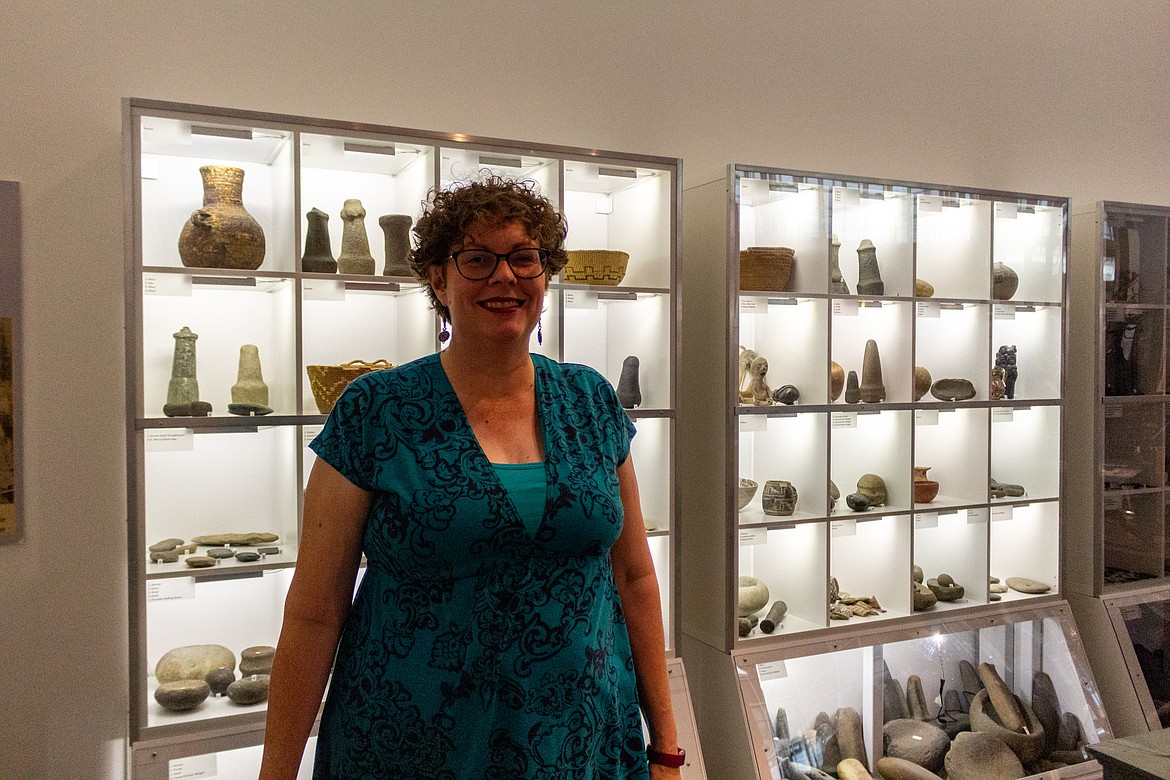 Moses Lake Museum & Art Center Manager Dollie Boyd stands in front of exhibits from the Adam East archaeological collection at the museum.