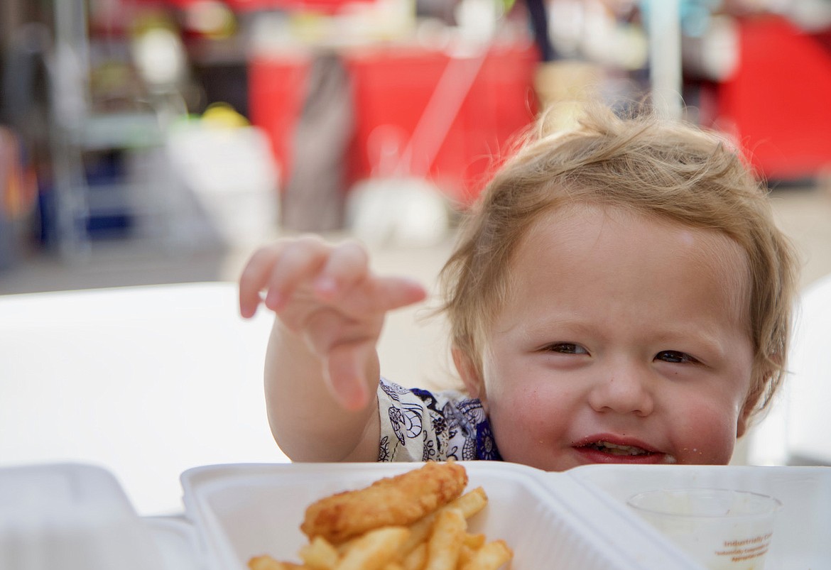 Little Hendrix goes for the fries while enjoying some of the food truck goodies at the Bigfork Festival of the Arts. (Kay Bjork photo)