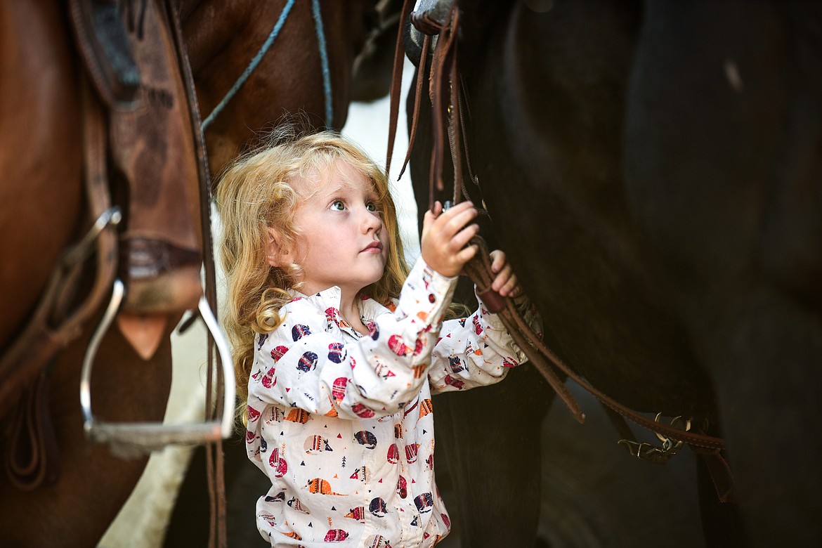 Ember McLean, 3, makes an adjustment to the saddle of her horse Beni before a ride at Ranch 'M near Kalispell on Tuesday, Aug. 10, 2021. (Casey Kreider/Daily Inter Lake)