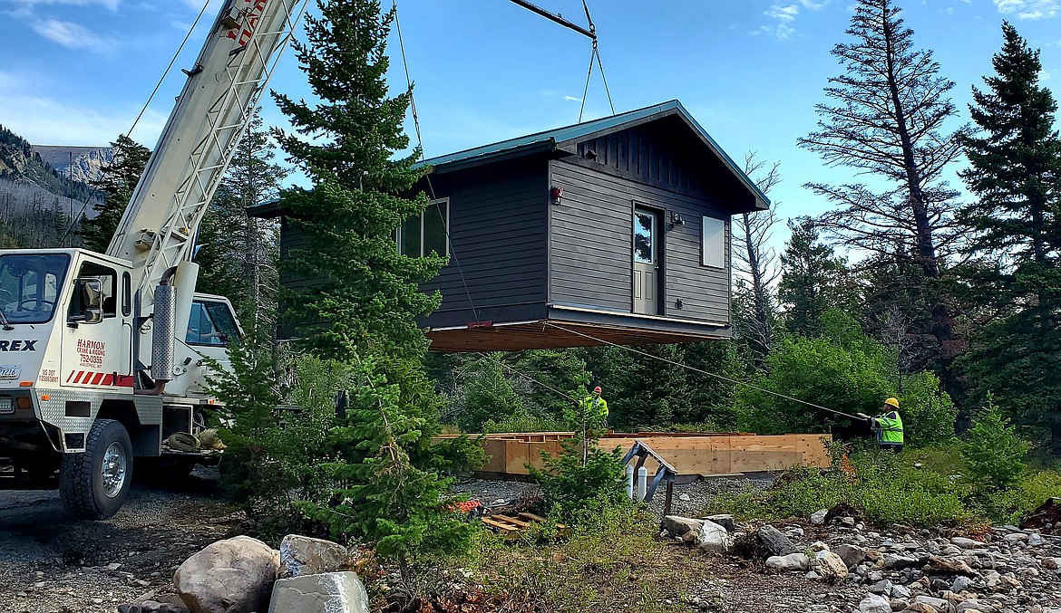 A crane lowers a two-bedroom cabin while a worker pulls a rope to guide it onto its foundation at the Rising Sun Campground in Glacier National Park on Monday, Aug. 9, 2021. A dozen Columbia Falls High School students built the cabin through Glacier's School-to-Park Program. (Chad Sokol/Daily Inter Lake)