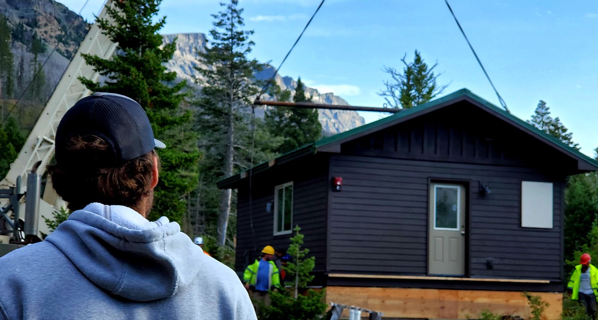 Cody Brothwell, who recently graduated from Columbia Falls High School and now works in facilities maintenance at Glacier National Park, watches Monday, Aug. 9, 2021, as a crane lowers a two-bedroom cabin onto its foundation at Glacier's Rising Sun Campground. Brothwell, 18, was one of a dozen students who built the cabin through Glacier's School-to-Park Program, a partnership with the Columbia Falls School District that teaches students building trades. (Chad Sokol/Daily Inter Lake)