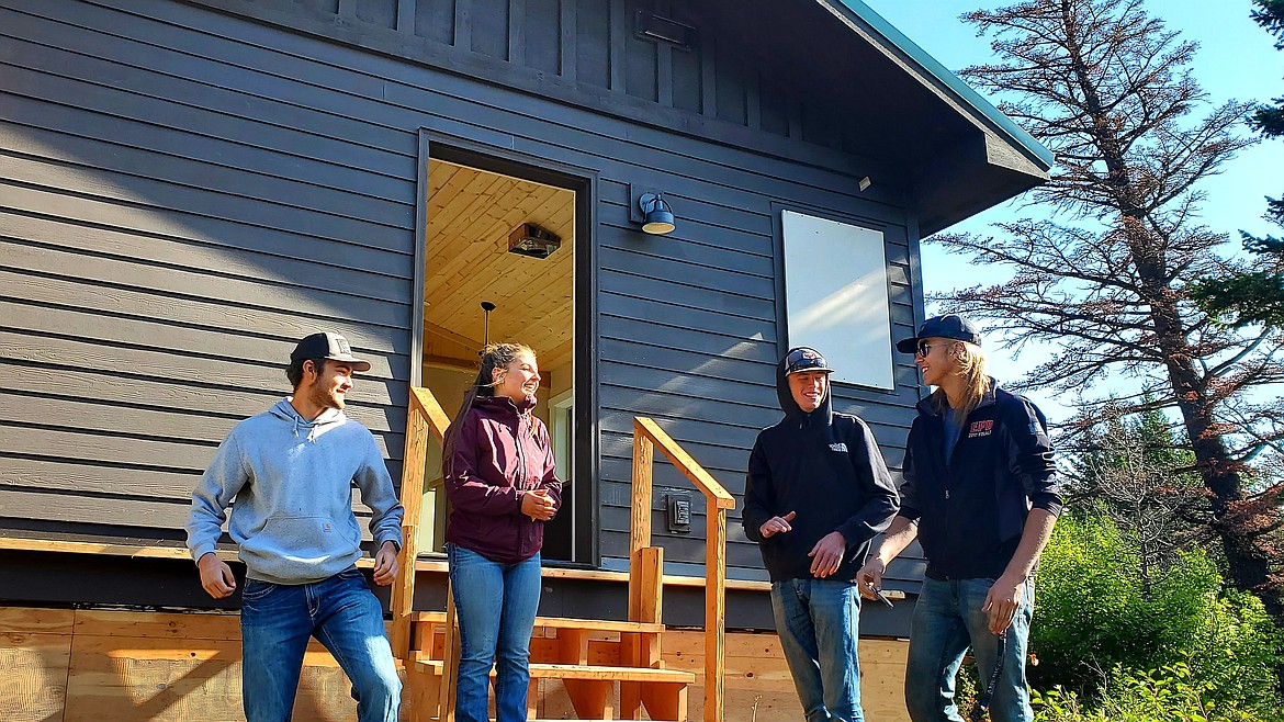 Cody Brothwell and Mae Anderson, at left, and two other peers from Columbia Falls High School stand in front of the two-bedroom cabin they built shortly after it was placed at the Rising Sun Campground on Monday, Aug. 9, 2021. The students built the cabin through Glacier's School-to-Park Program. (Chad Sokol/Daily Inter Lake)