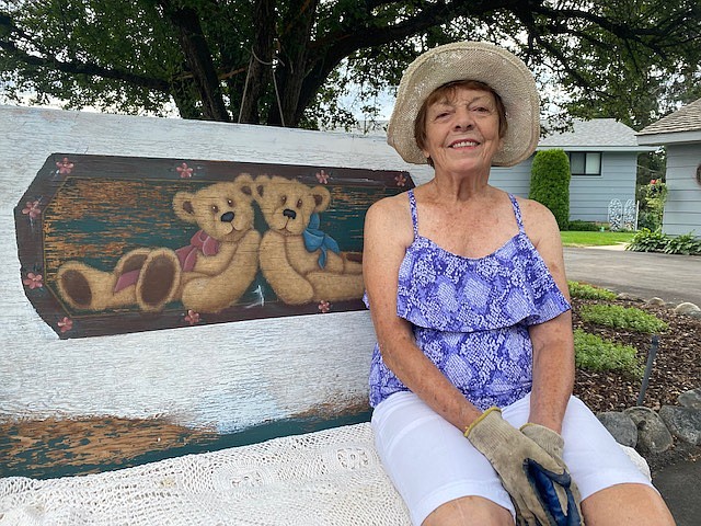 Roberta "Bertie" Smith sits upon an old wood bench she acquired and adorned with hand-painted teddy bears and a thrift store lace throw