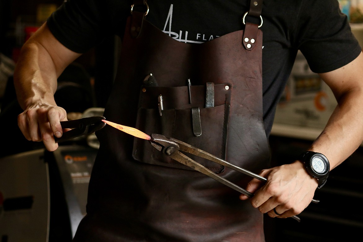 Andrew Hall, Coeur d'Alene resident and recent winner of the competition TV series "Forged in Fire," bends a curl into the tip of steel round stock in his garage workshop. HANNAH NEFF/Press