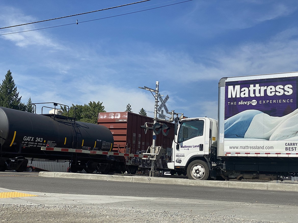 Eight cars lined up waiting for a BNSF train to pass on Mill Street through downtown Rathdrum Tuesday afternoon. After six minutes and dozens of cars flew by, the signals lifted, allowing traffic to continue. (MADISON HARDY/Press)