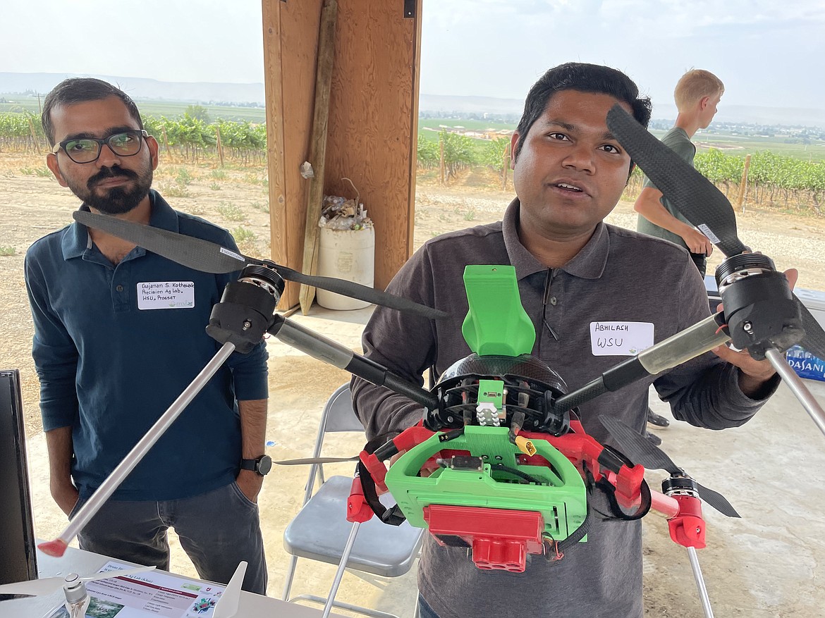 Washington State University researchers Grajanan Kothawade (left) and Abhilash Chamdel (right) show off drones used to take pictures of fields and orchards. Chamdel is holding a custom-built drone that not only takes pictures in visible light, but also in infrared, and can be merged with other data gathered from other field and orchard sensors.