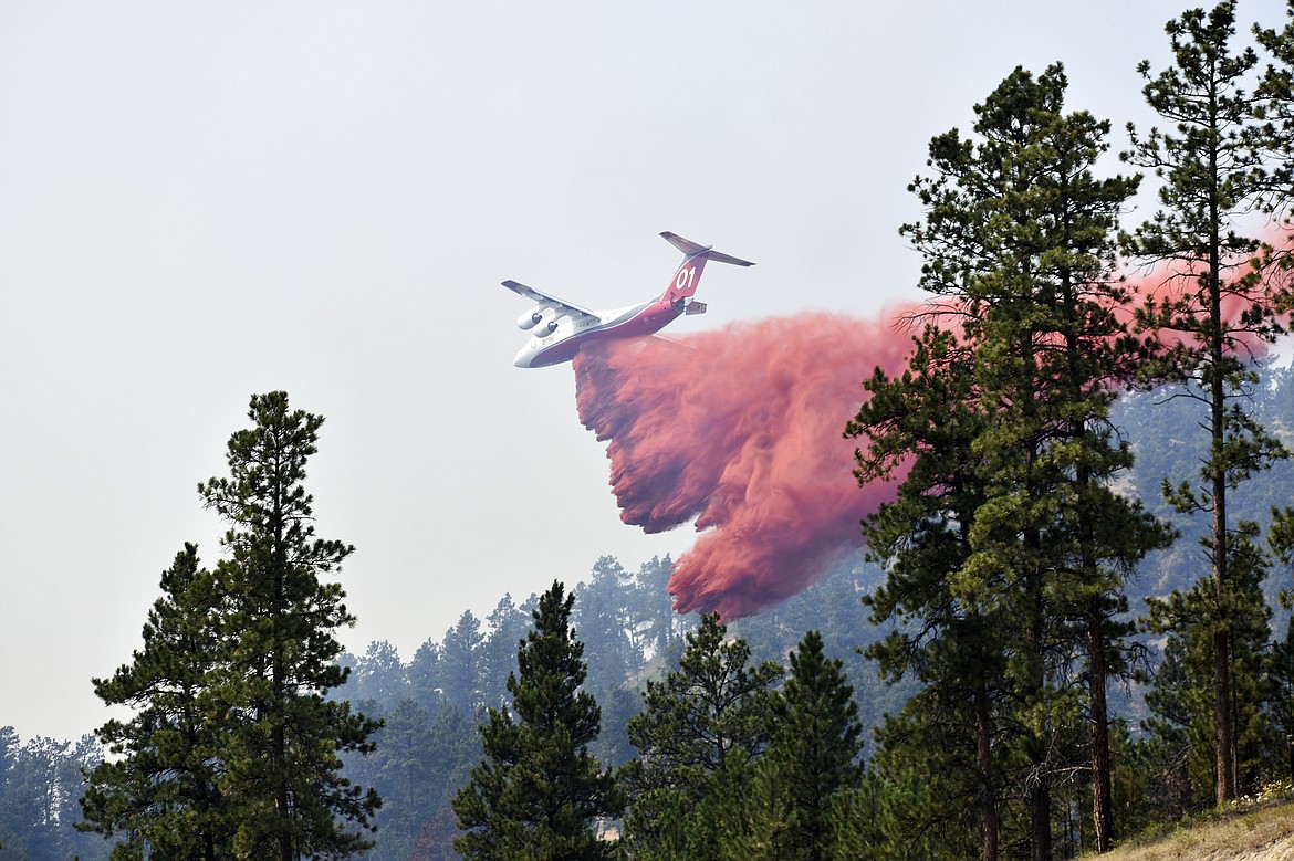 An aircraft drops fire retardant to slow the spread of the Richard Spring fire, east of Lame Deer, Mont., Wednesday, Aug. 11, 2021. The fire spread quickly Wednesday as strong winds pushed the flames across rough, forested terrain. (AP Photo/Matthew Brown)