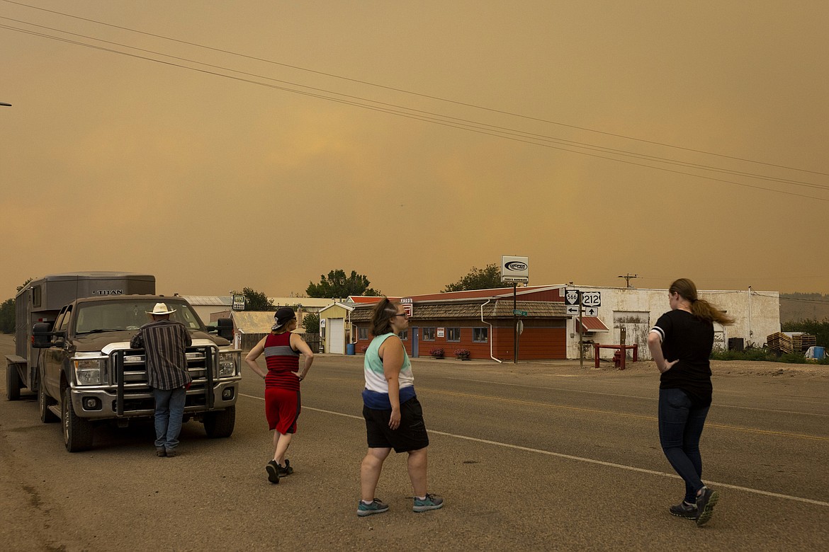 People are seen on the street as a wildfire approaches the town, Tuesday, Aug. 10, 2021, in Ashland, Mont. The Richard Spring Fire was threatening hundreds of homes in Ashland and on the nearby Northern Cheyenne Indian Reservation. (Mike Clark/The Billings Gazette via AP)