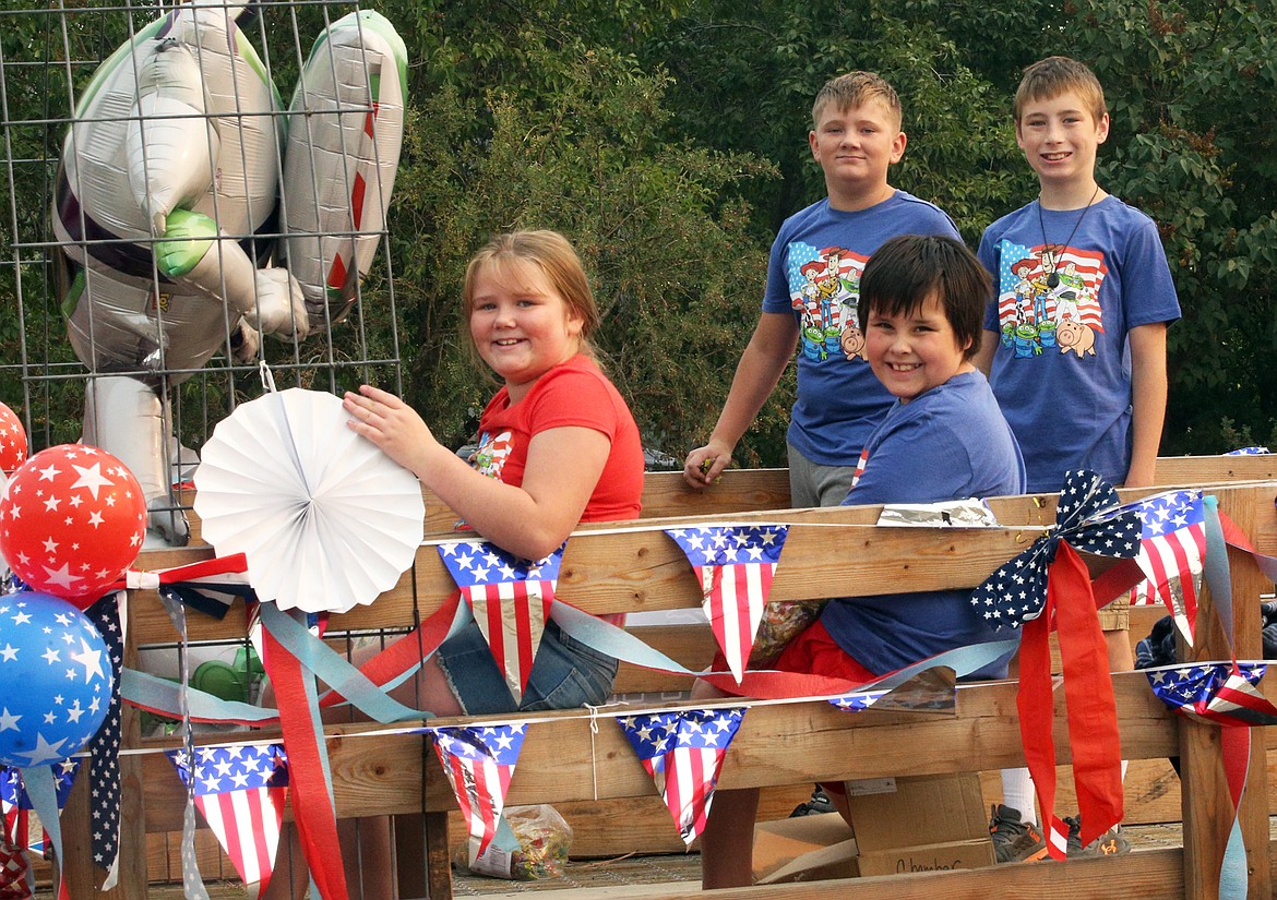 Lizzy Kuykendall and Jaxon Cameron, sitting, and Blake Kuykendall and Michael Holecek ride in the Athol  Chamber of Commerce float on Saturday.