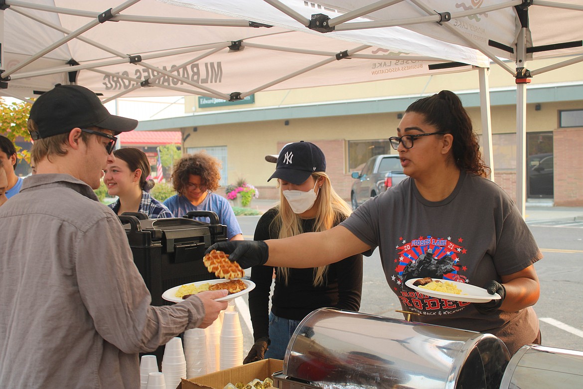 Kiwanis Club member Andrea Carrillo (right) serves waffles at the Cowboy Breakfast Friday morning.