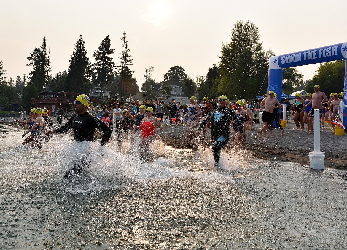 Swimmers run into Whitefish Lake Saturday morning for the annual Swim the Fish swim race at City Beach. More than 100 swimmers participated in the event, which includes a 5K, 1 mile and half-mile swim. The event is a fundraiser for the WAVE’s scholarship fund. (Heidi Desch/Whitefish Pilot)