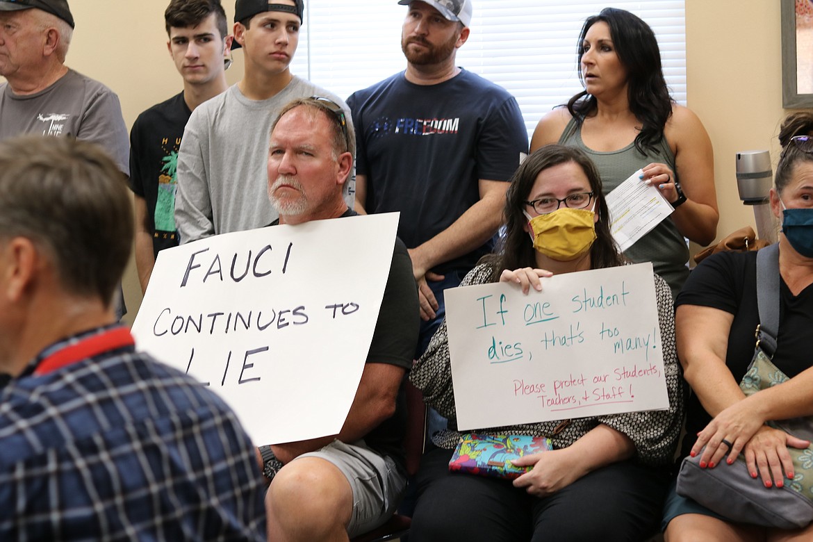 Janie Arambarri, masked and seated on right, holds a sign at the special meeting of the Coeur d’Alene School District Board of Trustees on Monday evening where reopening plans for the school, including whether or not to mandate masks, was discussed. HANNAH NEFF/Press