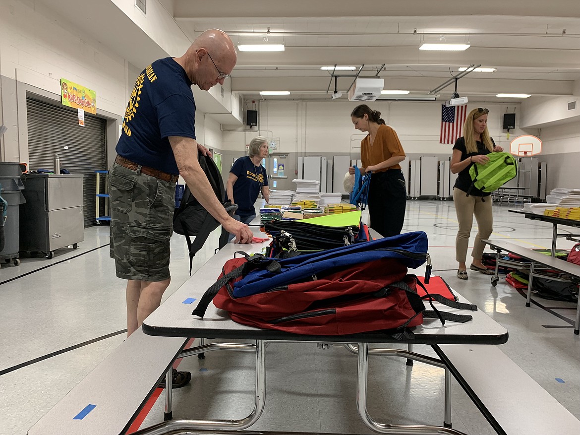 Rotary Club of Moses Lake President Terry Leas, front, and other volunteers from the club gather school supplies in backpacks for the club’s annual Backpacks 4 Kids event at Larson Heights Elementary School.