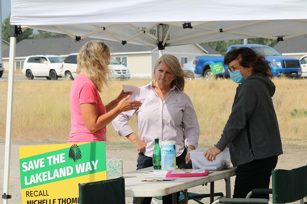 Terri Skubitz, center, and Debbie Andrews, right, speak with Jacque Zimmerman at a petition signing to recall Michelle Thompson, board chair of the Lakeland Joint School District board of trustees. Skubitz and Andrews ran the booth at the intersection of highways 41 and 53 on Tuesday. HANNAH NEFF/Press